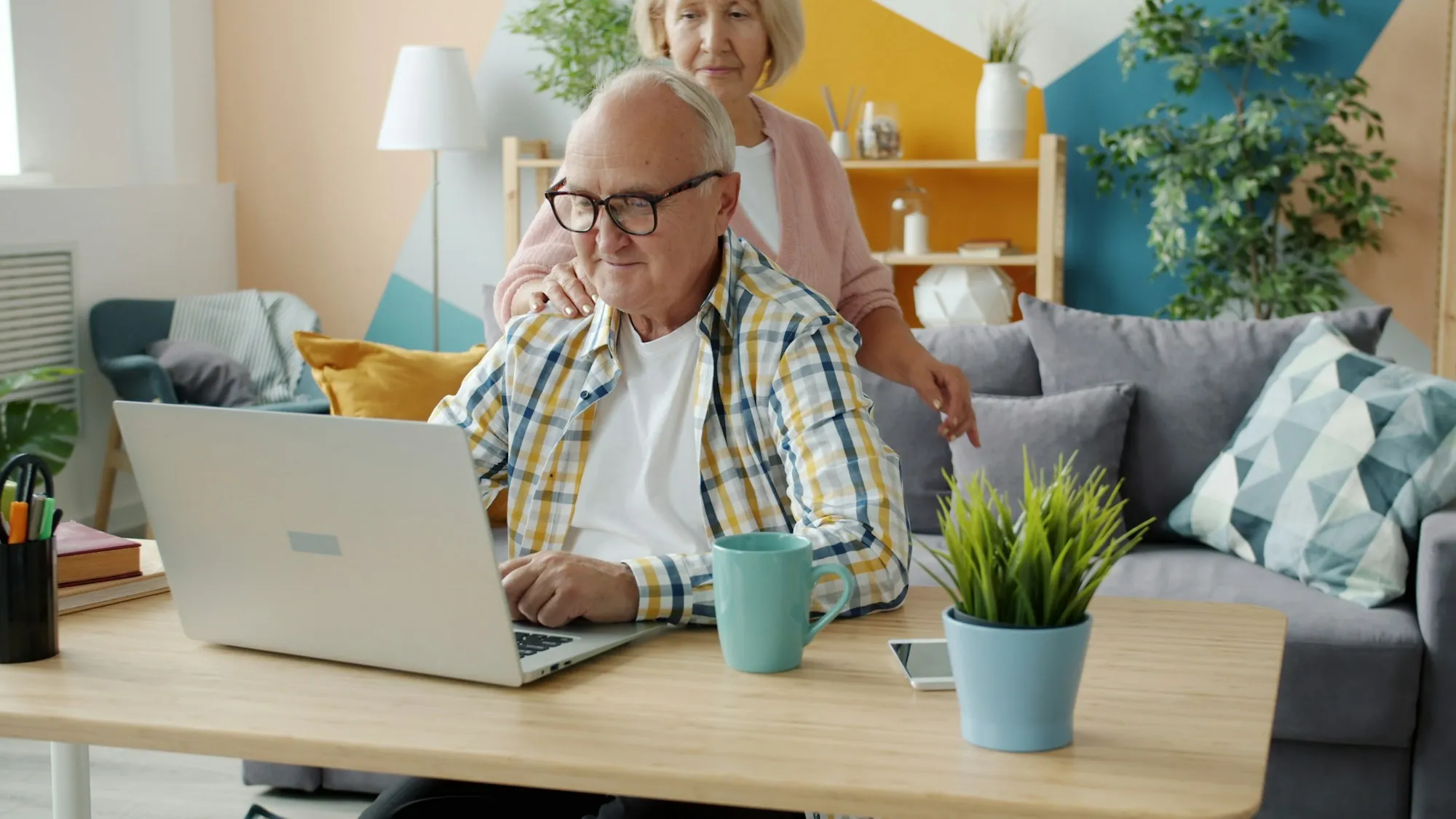 Older man at a laptop with his wife beside him