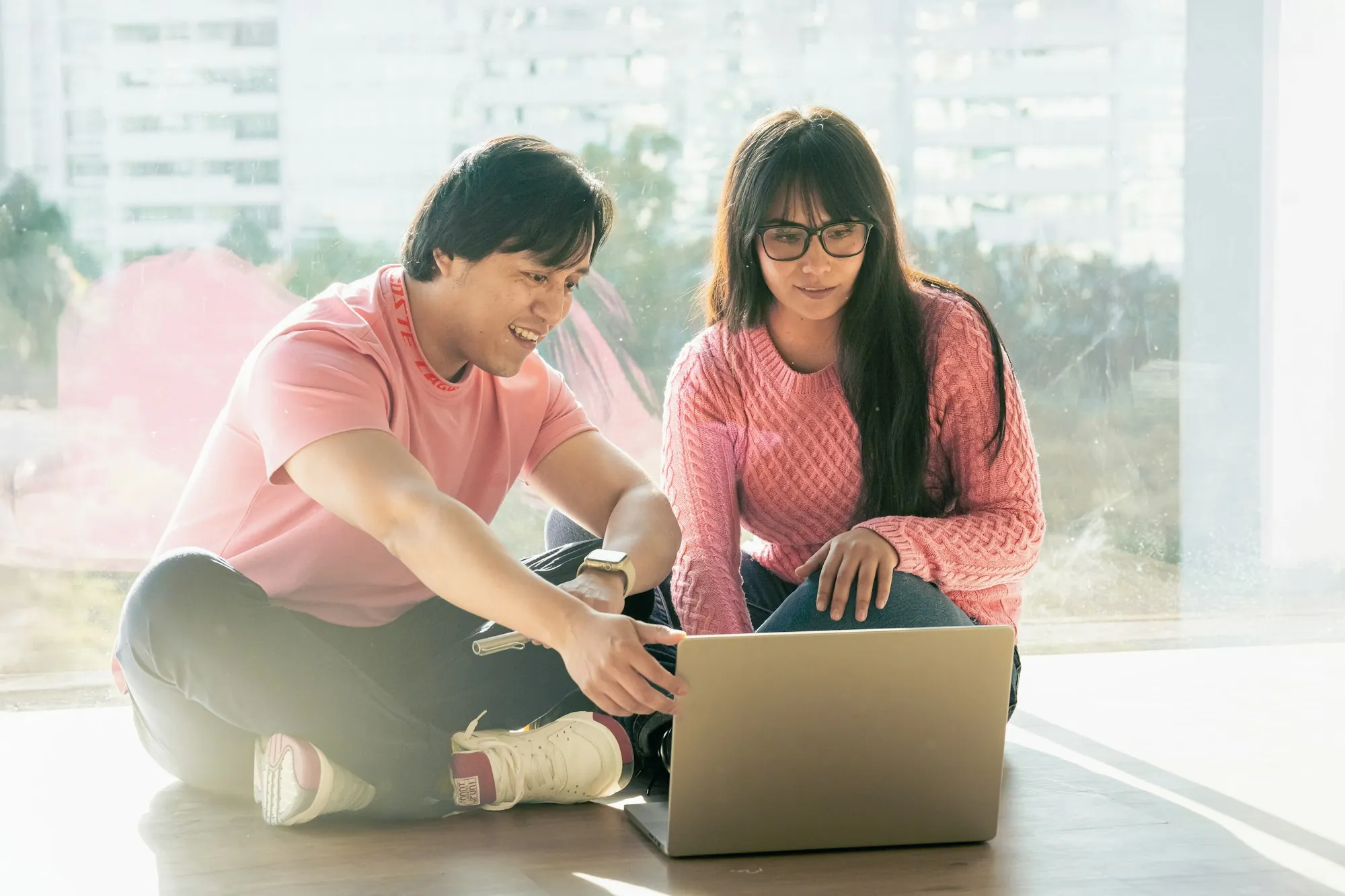 Couple sitting on the floor reviewing a laptop